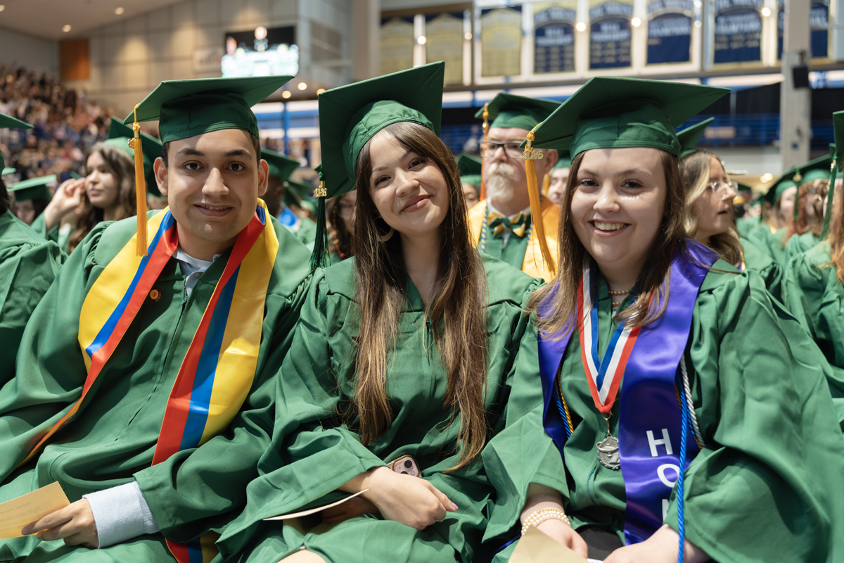 A graduate smiling broadly while walking across the stage at Commencement
