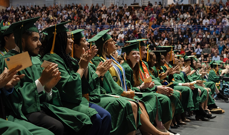 A row of graduates standing up to be recognized during the commencement