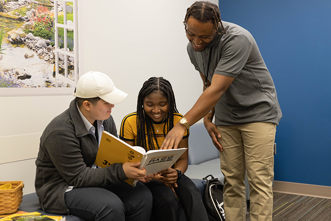 3 students looking at book